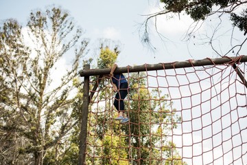 Obraz premium Fit woman climbing a net during obstacle course