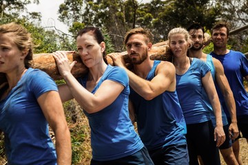 People carrying a heavy wooden log during boot camp