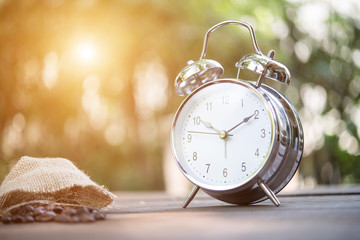 Retro alarm clock on wooden table. Nature background.