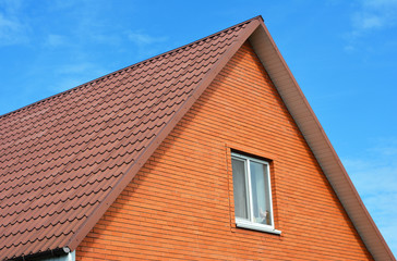 Red metal  sheets house roof tiles. Metal Roof Shingles - Roofing Construction, Attic Exterior, Roofing Repair. Brick House.
