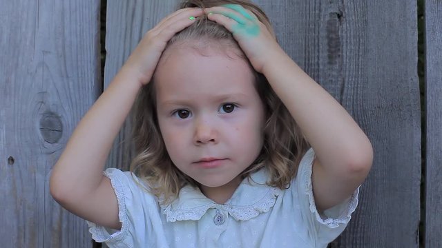 Little Beautiful Girl Holding Hands on Her Head With a Hand Stained in Green Paint