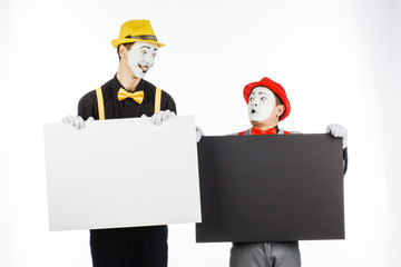 Two funny mimes holding a white blank on a white background.