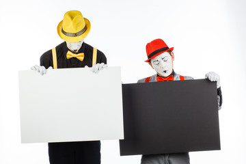 Two funny mimes holding a white blank on a white background.