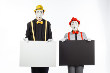Two funny mimes holding a white blank on a white background.
