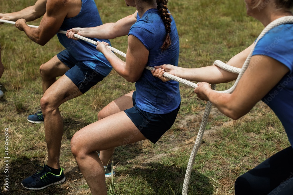 Wall mural People playing tug of war during obstacle training course