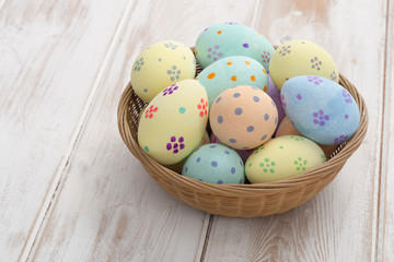 Painted Pastel-Colored Eggs in Wicker Bowl with Copy Space