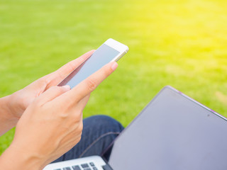 Pretty Young woman using smart phone. Female working on cell phone on green grass field