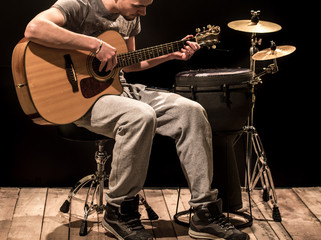 Fototapeta premium musician plays acoustic guitar and percussion instruments, black background