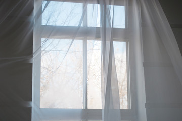 White transparent curtains on the window with spring blue sky