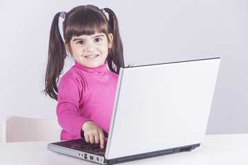 Cute little girl having fun using a laptop computer. Education, technology and e-learning concept