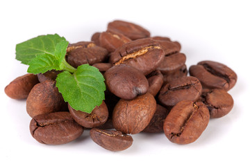 Pile of coffee beans with a mint leaf isolated on white background