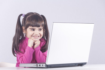 Cute little girl having fun using a laptop computer. Education, technology and e-learning concept