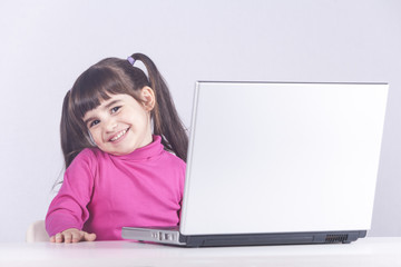 Cute little girl having fun using a laptop computer. Education, technology and e-learning concept