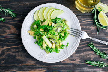 Healthy vegetarian food salad ingredients avocado, apples, kiwi, salad decorated with lime and rosemary on the wooden table top view