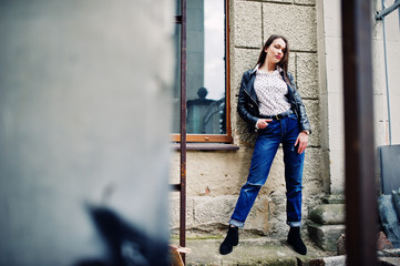 Portrait of stylish young girl wear on leather jacket and ripped jeans at streets of city. Street fashion model style.