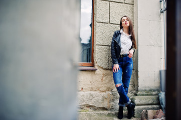 Obraz na płótnie Canvas Portrait of stylish young girl wear on leather jacket and ripped jeans at streets of city. Street fashion model style.
