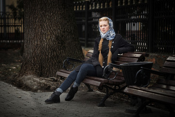 Beautiful red-haired girl sitting on a bench