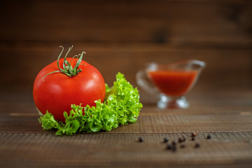 Sauce, lettuce and tomatoes on a wooden background. The concept of healthy eating and vegetarianism.