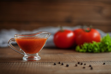 Ketchup and tomatoes on a wooden background. The concept of healthy eating and vegetarianism.