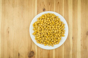 Bowl of chickpeas on wood table. Cooked gram-chick peas on a plate photographed from the top