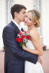 Young couple in wedding gown. Bride holding bouquet of flowers