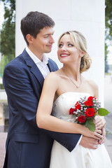 Young couple in wedding gown. Bride holding bouquet of flowers