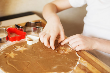 Children's hands make gingerbread. Small boy cutting cookies for Christmas. Kid Baking Cooking Cookies Fun Concept