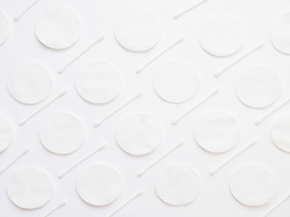 Abstract pattern of cotton pads and cotton swabs on white background. Textured white background.