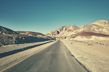 Fototapeta na wymiar Retro toned picture of a desert road in Death Valley, California, USA.
