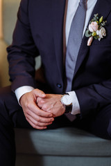 groom in black suit with expensive watches sitting in the chair close-up of hands