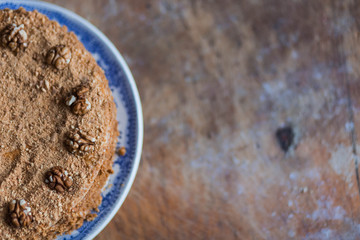 honey cake in blue white plate on light brown wooden background copyspace