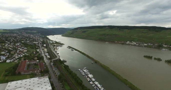 The city of Bingen lies peacfully along the river Rhine. The boats are in the harbour. It is a partly clouded day.