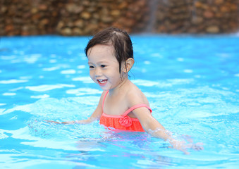 Fototapeta na wymiar Pretty little girl playing in swimming pool outdoors