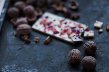 white chocolate with red berries and walnut whole nuts on black background