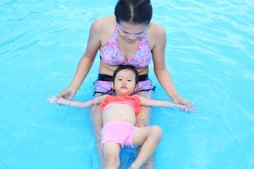 Fototapeta na wymiar Pretty little girl with her mother in swimming pool outdoors