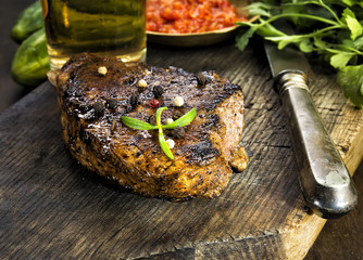 Steak with herbs and beer on a wooden background