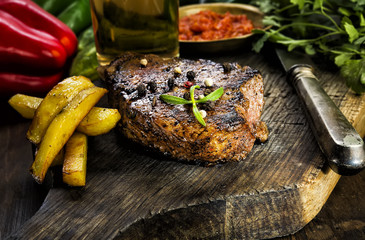 Steak with herbs and beer on a wooden background