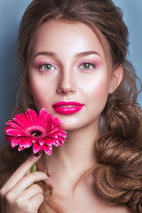 Portrait of romantic young woman with pink flower looking at camera on blue background .  Spring fashion photo. Inspiration of spring and summer. Perfume, cosmetics concept.