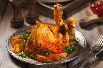 Baked chicken leg, served with roasted potatoes and vegetables.