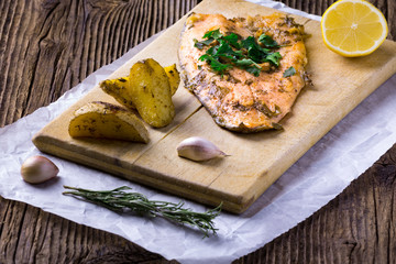 Trout with potateos on wooden board.