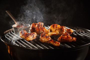 Spicy chicken legs grilling on a smoking fire
