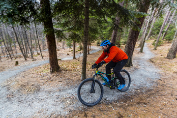 Obraz na płótnie Canvas Mountain biker riding on bike in early spring mountains forest landscape. Man cycling MTB enduro flow trail track. Outdoor sport activity.