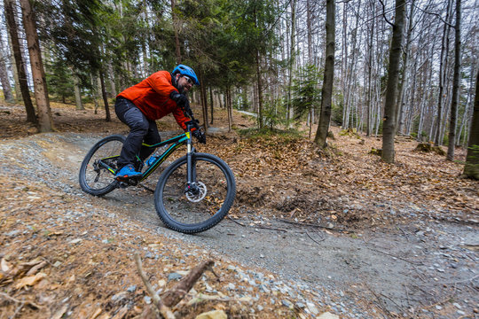 Mountain biker riding on bike in early spring mountains forest landscape. Man cycling MTB enduro flow trail track. Outdoor sport activity.