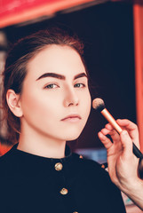 Obraz premium Make-up artist doing make-up of a beautiful young girl in the studio