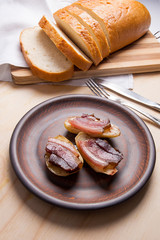 Baked potatoes with slices of bacon on wooden background. Slices of white bread on cutting board.