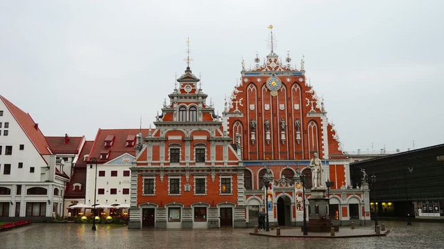 Riga, Latvia. House of the Blackheads in the old town of Riga, Latvia. Unidentified blurred people walking by the square during the rain. Time-lapse with cloudy sky