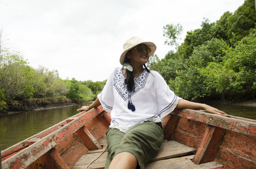 Traveller thai woman sit on service long tail boat for looking and travel view riverbank and Mangroves forest or Intertidal forest on river of Pak Nam Prasae