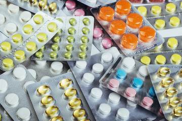 Pills of different colors lie on the surface in a sealed package.