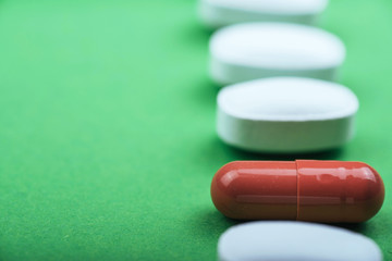Medical white pills and brown capsules for the treatment and health care on a green background