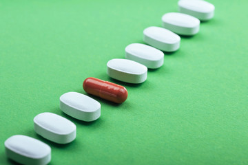 Medical white pills and brown capsules for the treatment and health care on a green background